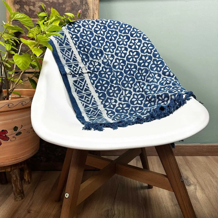 A handmade indigo runner with blue and white floral pattern frayed edges and geometric border made of textile