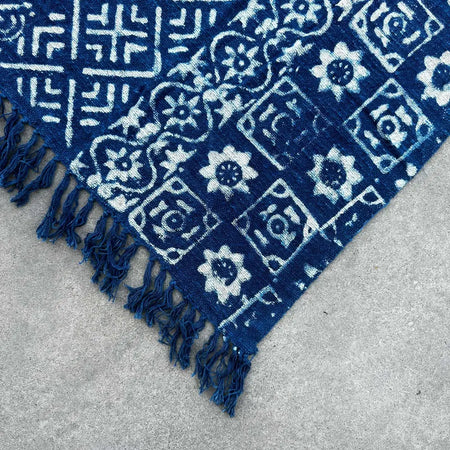 Handmade indigo throw with deep indigo blue fabric white block-printed floral and geometric patterns and frayed edges