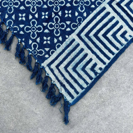 A handmade indigo throw with navy blue indigo-dyed fabric and white block-printed kasba tiles pattern and fringed edges