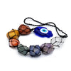 Hanging chakra stone pendant with seven colorful polished stones wrapped in black macrame and a blue evil eye charm