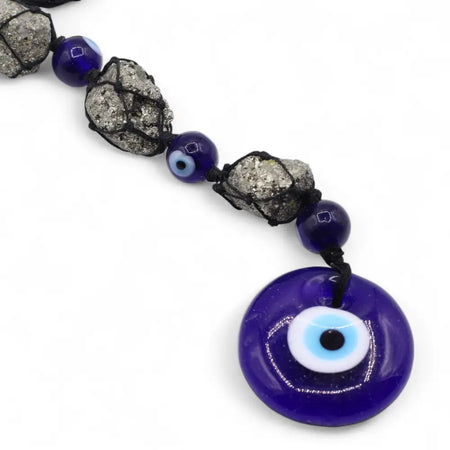 A hanging stone pendant featuring a cobalt blue evil eye charm with pyrite stones and matching beads on a cord