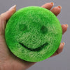 Happy scrub soap bar coconut is a vibrant green round scrub soap made from natural fibers with a smiley face design