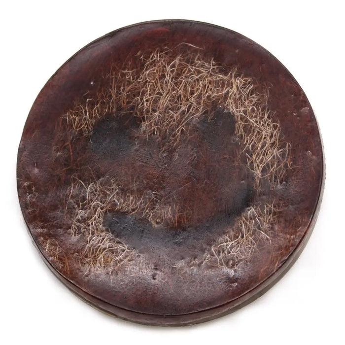 A dark brown leather coaster with textured surface and light fibers holds a happy scrub soap bar coconut soap bar