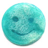 A translucent turquoise resin smiley face coaster with white fibrous texture paired with raspberry pomegranate scrub soap bar