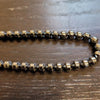 A sleek dark metallic hematite beaded necklace with faceted hexagonal barrel beads and a polished finish