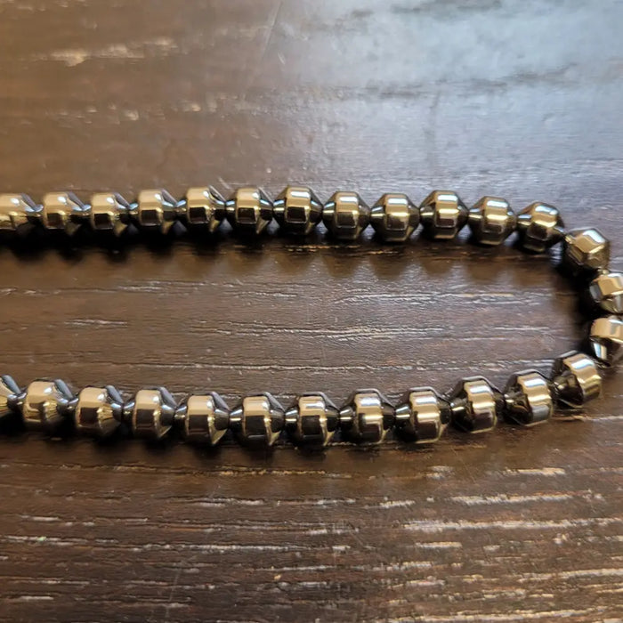 A sleek dark metallic hematite beaded necklace with faceted hexagonal barrel beads and a polished finish