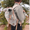 A beige and gray herringbone-patterned hemp trekking rolling backpack with tan straps made from natural materials