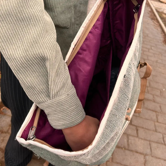 A hemp trekking rolling backpack in sage green with herringbone pattern purple interior and tan zipper pulls made from hemp materials