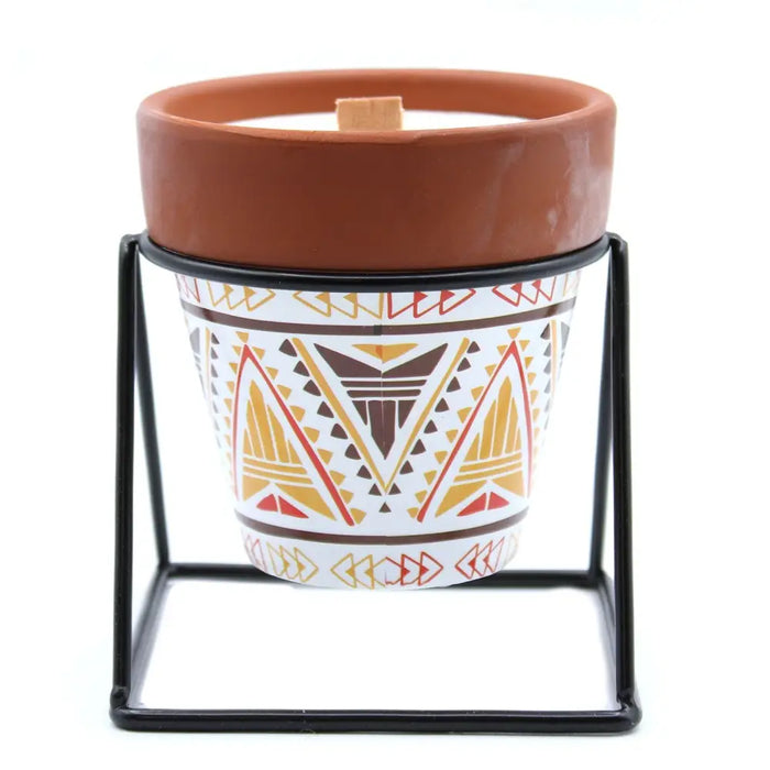 A terracotta herb garden candle with sage scent in a white ceramic pot with brown and gold geometric patterns made of soy wax