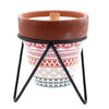 A terracotta herb garden scented candle holder with red and white geometric pattern on black metal stand with soy wax