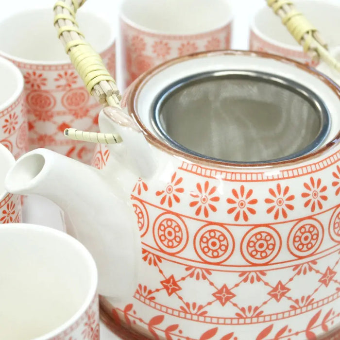 White ceramic teapot with orange floral patterns and bamboo handle wrapped in green twine from herbal teapot set amber