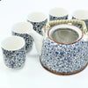 Blue and white ceramic teapot with intricate leaf patterns, bamboo handle, and metal strainer for herbal brewing