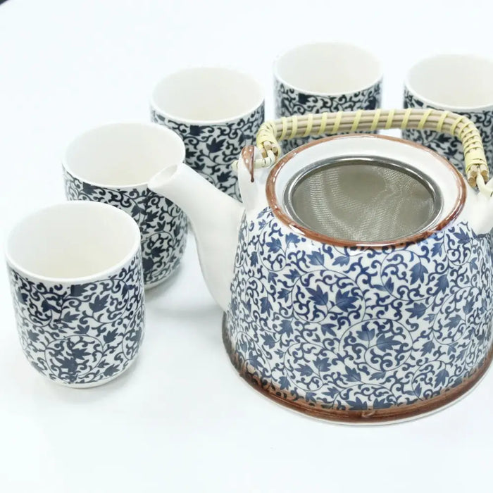 Blue and white ceramic teapot with intricate leaf patterns, bamboo handle, and metal strainer for herbal brewing