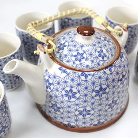 A ceramic herbal teapot with white body, blue geometric floral patterns, brown lid and rim, and bamboo handle