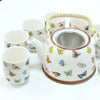 White ceramic teapot with colorful butterfly decals, woven handle, and metal infuser for herbal tea brewing