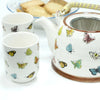 White ceramic teapot with colorful butterfly decals brown rim and metal infuser inside from herbal teapot set butterflies