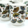 White ceramic mug with colorful traditional fan patterns as part of a herbal teapot set design