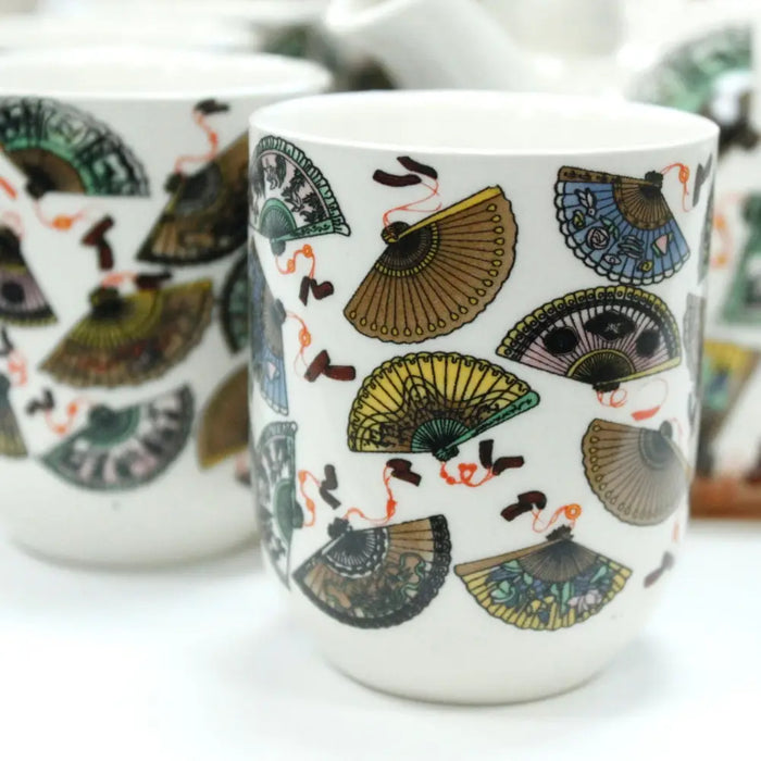 White ceramic mug with colorful traditional fan patterns as part of a herbal teapot set design