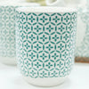 White ceramic mug with teal four-petaled flower pattern from herbal teapot set green mosaic