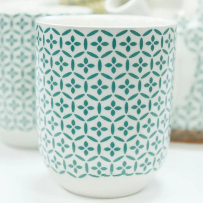 White ceramic mug with teal four-petaled flower pattern from herbal teapot set green mosaic