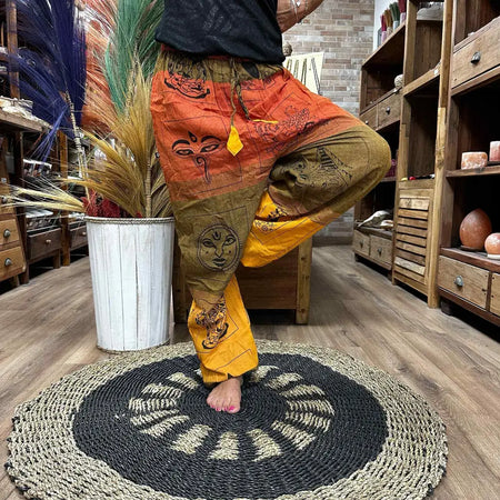 High cross yoga and festival pants in orange and mustard yellow with black spiritual motifs and harem style fit