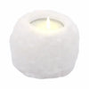 A white himalayan salt tealight holder made of textured crystal rock with a lit candle inside