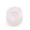 A white himalayan salt crystal rock tealight holder with a textured surface holding a small round candle