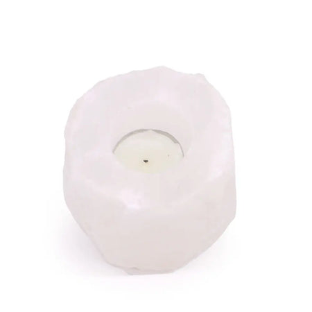 A white himalayan salt crystal rock tealight holder with a textured surface holding a small round candle