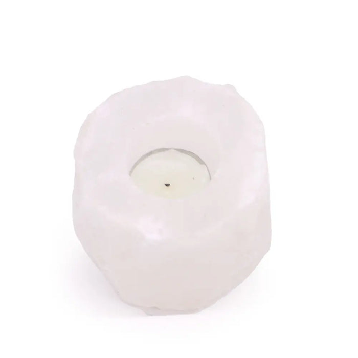 A white himalayan salt crystal rock tealight holder with a textured surface holding a small round candle