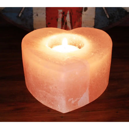 A heart-shaped himalayan salt tealight holder with a warm pinkish-orange hue and natural crystalline texture