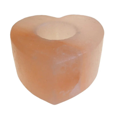 A heart-shaped pink himalayan salt tealight holder with a translucent, slightly rough texture and a central opening