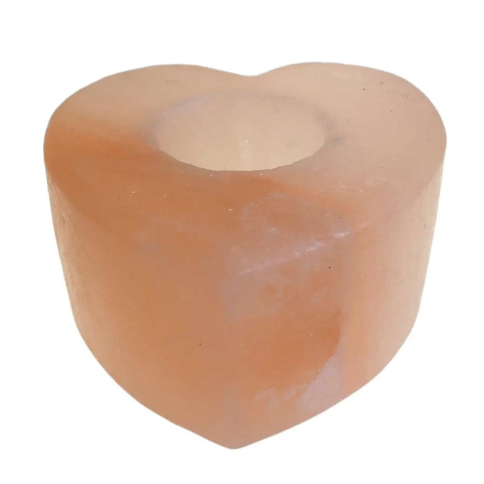 A heart-shaped pink himalayan salt tealight holder with a translucent, slightly rough texture and a central opening