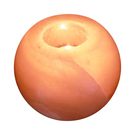 A smooth round orange candle with a central wick hole in a himalayan salt tealight holder round design