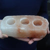 A rectangular pink himalayan salt brick with three circular holes designed as tealight holders