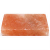 A rectangular pink himalayan salt cooking plate with a rough surface and subtle mineral inclusions