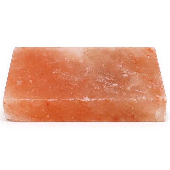 A rectangular pink himalayan salt cooking plate with a rough surface and subtle mineral inclusions