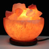 A glowing orange himalayan salt lamp in a rough stone bowl with pinkish-orange salt crystals showing its hygroscopic properties