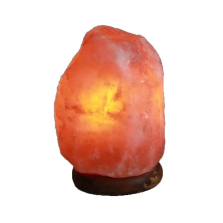 A warm glowing himalayan salt lamp with an orange pink crystal on a dark wooden base weighing 1.5 to 2 kg