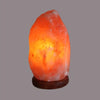 A glowing orange himalayan salt lamp with rough texture and warm light weighing 2-3kg made from natural salt lamp
