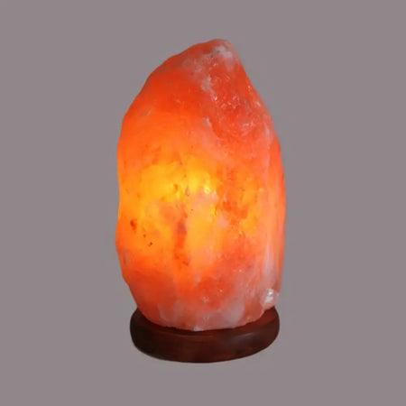 A glowing orange himalayan salt lamp with rough texture and warm light weighing 2-3kg made from natural salt lamp