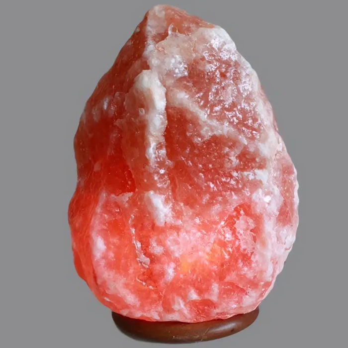 A himalayan salt lamp with pink and white hues on a dark wooden base known for hygroscopic properties in humid conditions