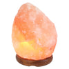 A warm glowing pink himalayan salt lamp with natural crystalline texture on a dark wooden base weighs 3-5kg