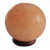 A smooth peach-colored himalayan salt lamp ball weighing 4kg on a dark wooden base showing its hygroscopic properties