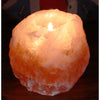 A warm glowing orange himalayan salt tealight holder with natural crystalline texture and a lit candle inside