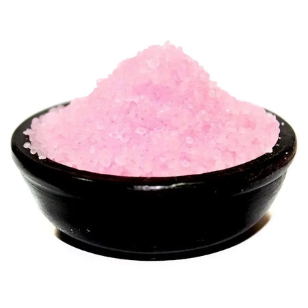 A bowl of coarse pink salt granules in a black ceramic bowl with subtle midnight roses notes for bedroom use