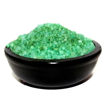 A sleek black ceramic bowl filled with vibrant green coarse simmering granules from home comforts floral greetings
