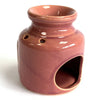 A glossy pink terracotta home oil burner with a rounded neck and ventilation holes for home oil use