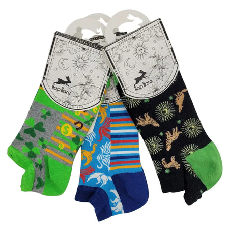 Three hoplare bamboo trainer socks in gray green shamrock, blue dinosaur, and black giraffe patterns with colorful accents