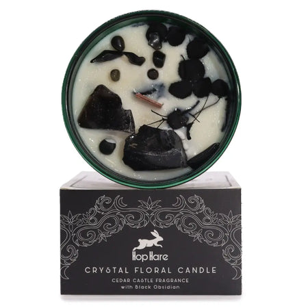 A white hop hare crystal magic flower candle with black obsidian and dried botanicals in a green tin on its box