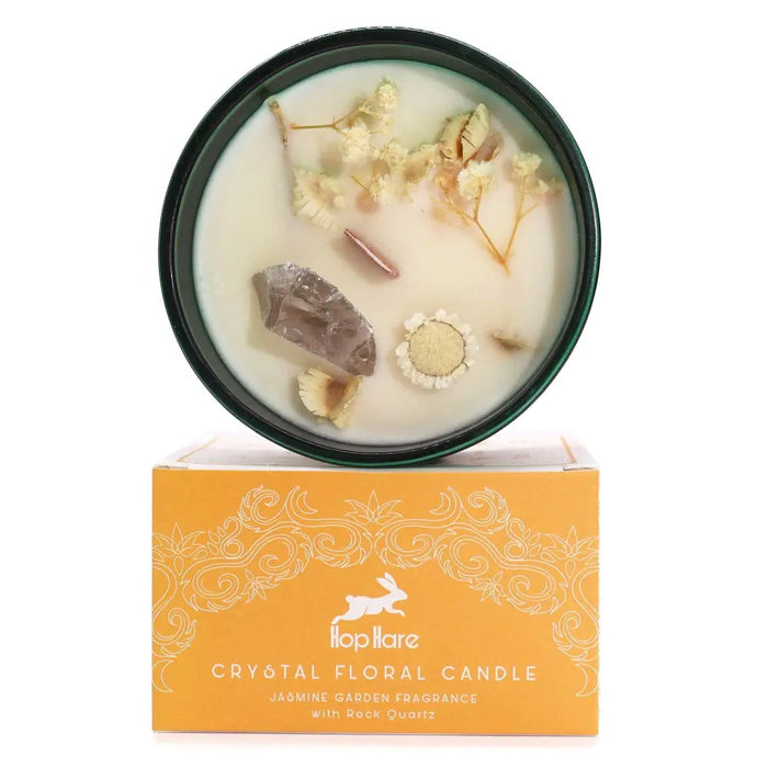 A hop hare crystal magic flower candle in a dark green container with white floral wax dried flowers and rock quartz